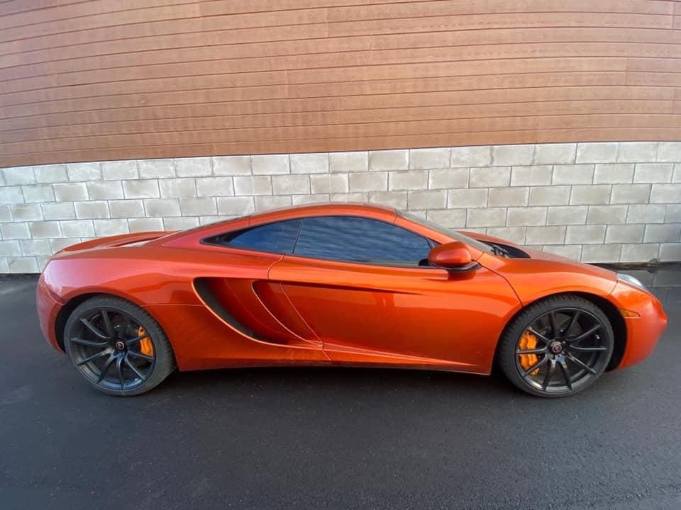 A red sports car parked in front of a brick wall.